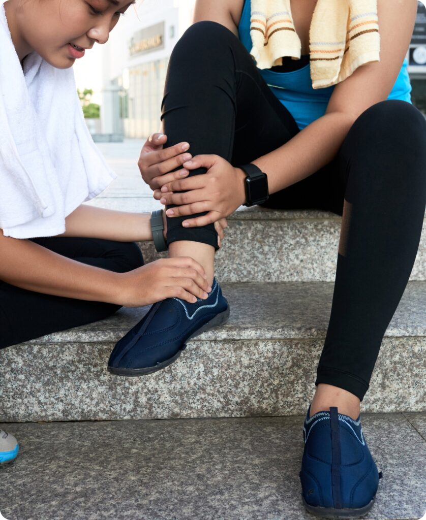 A physical therapist examining the ankle of a female runner sitting on outdoor steps, representing targeted care for ankle injuries.