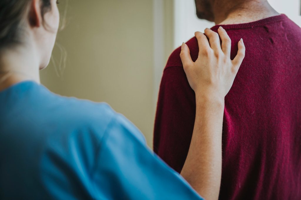 A healthcare professional placing a comforting hand on a patient's shoulder, representing compassionate, non-surgical joint care.