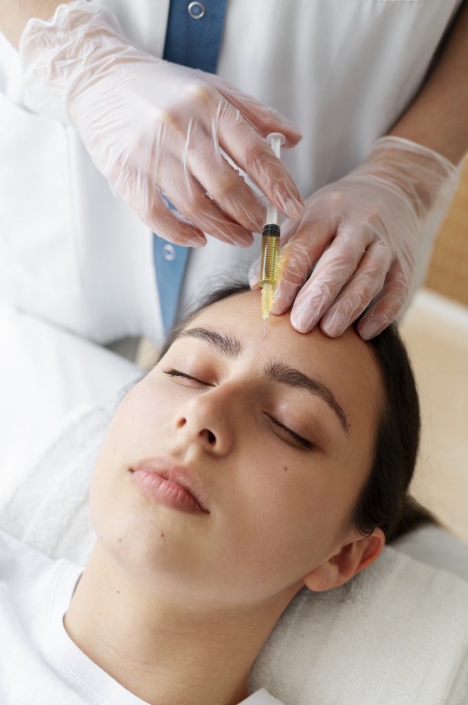 A medical professional administering a Platelet-Rich Plasma (PRP) injection into a female patient's forehead.