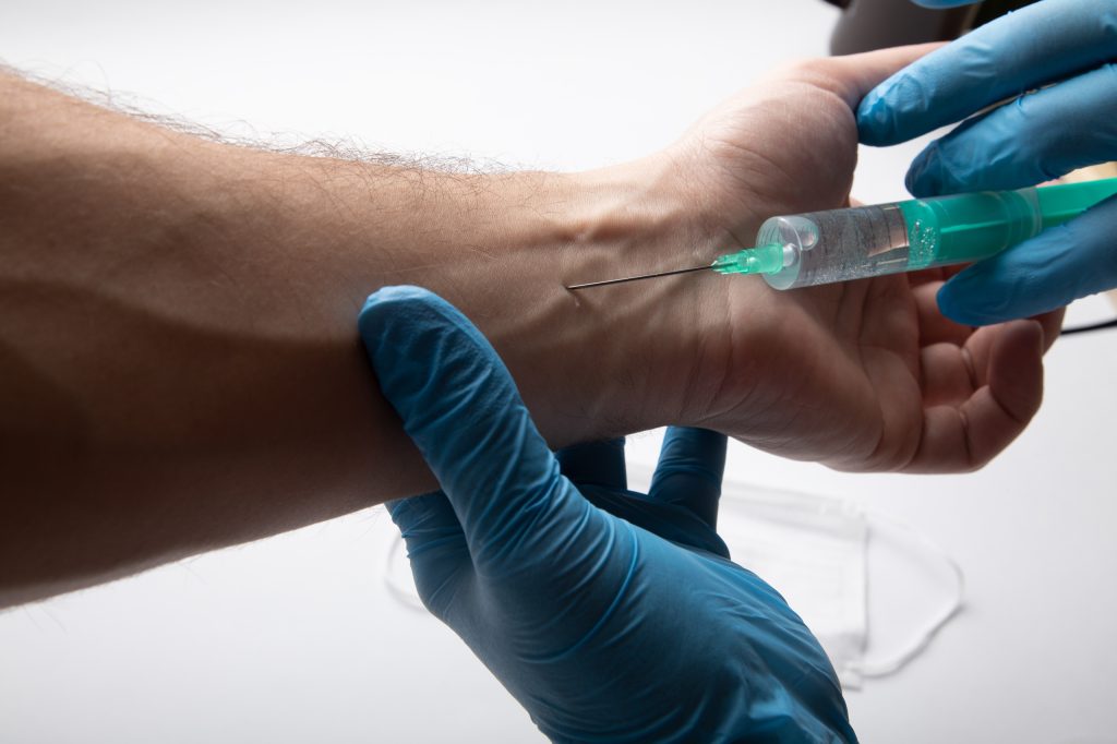 A clinician at Joint Health Solutions discussing the safety profile and potential side effects of trigger point injections with a patient in a sterile clinical room.