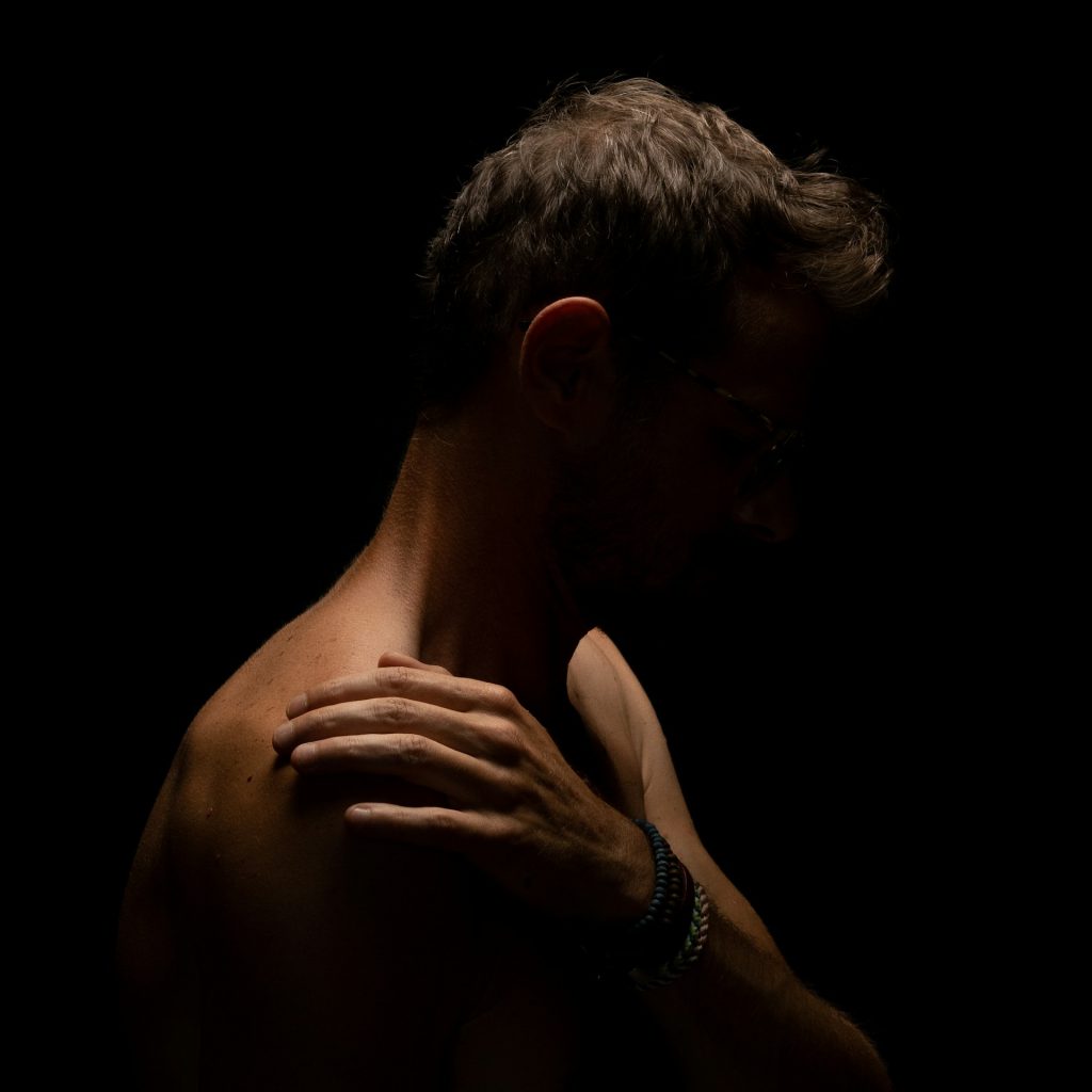 Patient holding painful shoulder during diagnosis evaluation